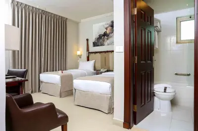a hotel room with two beds and a toilet at Retaj Hotel in Amman