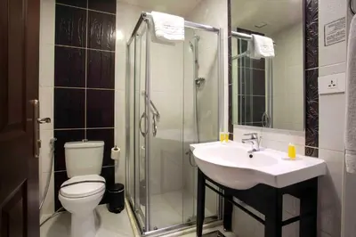 a bathroom with a toilet and a sink and a shower at Retaj Hotel in Amman