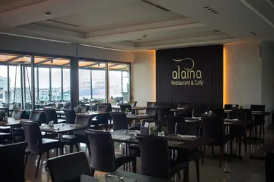 a restaurant with tables and chairs and a sign on the wall at Retaj Hotel in Amman