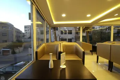 a restaurant with a table and chairs and a window at 360 Hotel By FHM in Amman