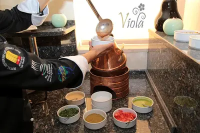 a person pouring food into a pot on a counter at Viola Hotel Suites in Amman