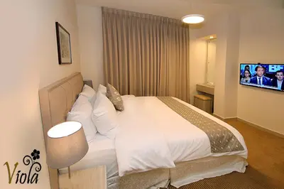 a bedroom with a large white bed and a tv at Viola Hotel Suites in Amman