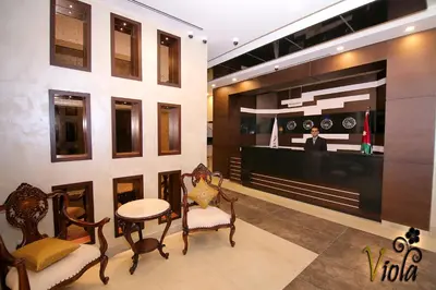 a lobby with chairs and a table and a counter at Viola Hotel Suites in Amman