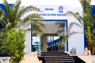 a blue and white building with stairs and palm trees at Aqaba Adventure Divers Resort & Dive Center in Aqaba