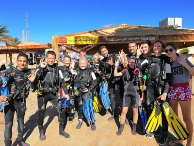 a group of people posing for a picture on the beach at Aqaba Adventure Divers Resort & Dive Center in Aqaba