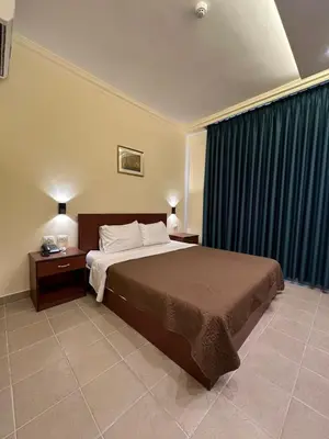 a bedroom with a large bed with blue curtains at Rumman Hotel in Madaba