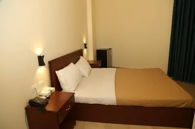 a bedroom with a bed and a nightstand with a phone at Rumman Hotel in Madaba