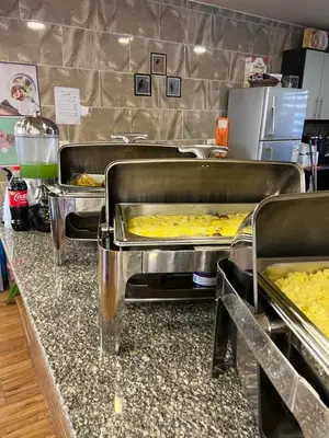 a buffet line with trays filled with food at Petra cabin Roof top hostel in Wadi Musa