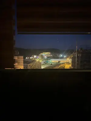 a view of a city at night from a window at Petra cabin Roof top hostel in Wadi Musa