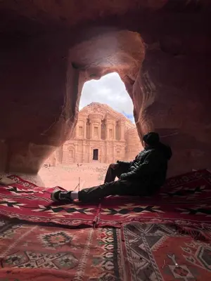 a man sitting on a rug in front of a building at Happy Bedouin House Petra in Al Ḩayy