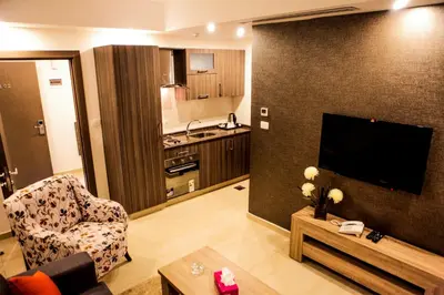 a living room with a television and a couch and a table at Almond Hotel Apartments in Amman