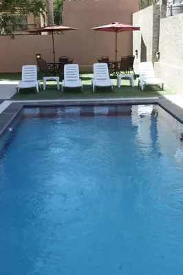a swimming pool with chairs and umbrellas in a building at Almond Hotel Apartments in Amman