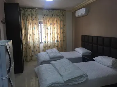 a room with three beds and a window at Al haramain Furnished Apartments in Amman