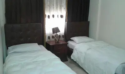 a bedroom with two beds and a table with a lamp at Al haramain Furnished Apartments in Amman
