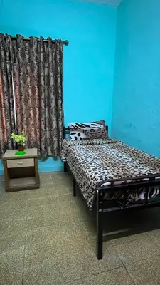 a bedroom with a bed and a table and a curtain at Cliff Hostel in Amman