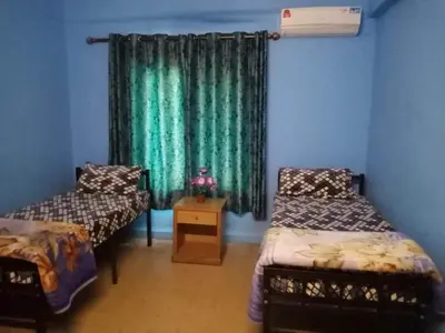 a room with two beds and a window with green curtains at Cliff Hostel in Amman