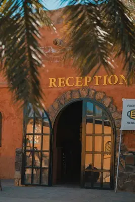an entrance to a red building with a sign that reads reception at Bait Ali in Wadi Rum