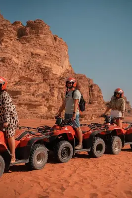 three people are riding on atvs in the desert at Bait Ali in Wadi Rum
