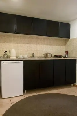 a kitchen with black cabinets and a white refrigerator at Barakat Hotel Apartments in Amman