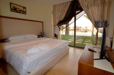 a bedroom with a bed and a tv and a window at Public Security Hotel & Chalets in Aqaba