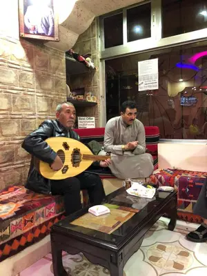 two men sitting on a table playing a guitar at Valentine Inn in Wadi Musa