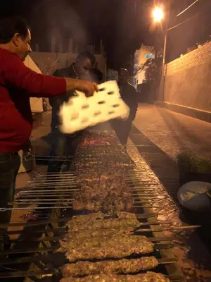 a man cooking food on a grill at night at Valentine Inn in Wadi Musa
