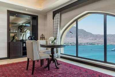 a living room with a table and chairs and a large window at Al Manara, a Luxury Collection Hotel, Aqaba in Aqaba