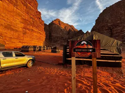 a sign in the desert with a car parked at Desert Rock camp in Wadi Rum