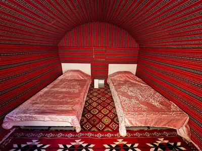a room with red walls with two beds in it at Desert Rock camp in Wadi Rum