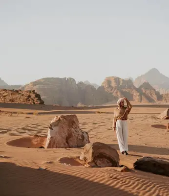 a woman standing in the desert near a rock at Hasan Zawaideh Camp in Wadi Rum