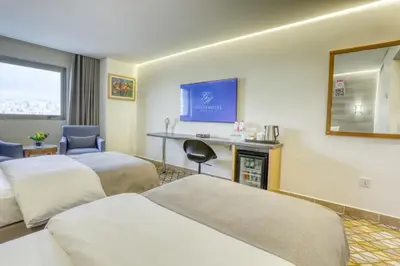 a hotel room with two beds and a flat screen tv at Geneva Hotel in Amman