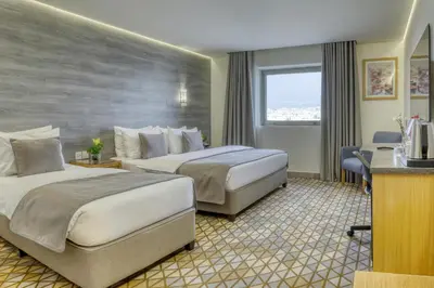 a hotel room with two beds and a desk at Geneva Hotel in Amman
