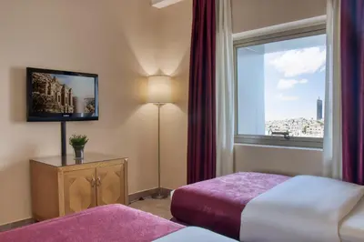 a hotel room with a bed and a window at Geneva Hotel in Amman