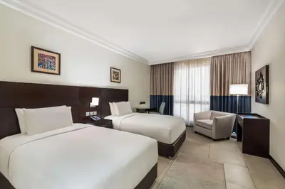 a hotel room with two beds and a chair at DoubleTree by Hilton Hotel Aqaba in Aqaba