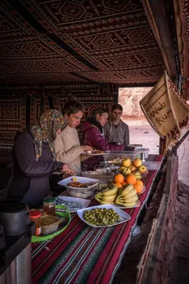 a group of people standing around a table with food at Arabian Nights in Wadi Rum