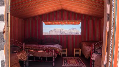 a room with two beds and two chairs in it at Arabian Nights in Wadi Rum