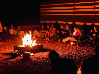 a group of people sitting around a fire at Wadi Rum Shooting Stars Camp in Wadi Rum