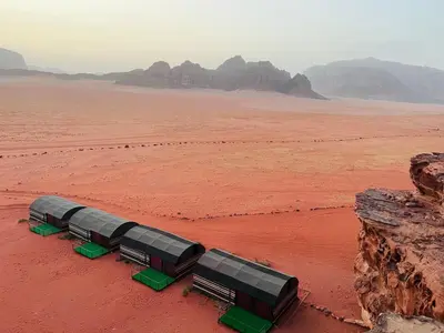 two buses in the desert with mountains in the background at Wadi Rum Shooting Stars Camp in Wadi Rum