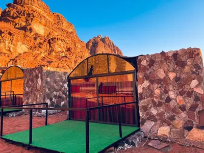 a building with two windows in front of a mountain at Wadi Rum Shooting Stars Camp in Wadi Rum