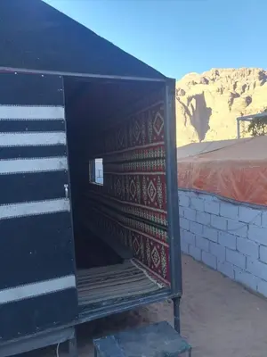 a black building with a door open with a desert at Climbers House in Wadi Rum in Wadi Rum