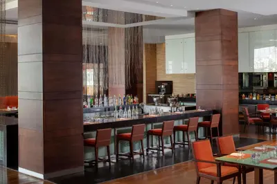 a bar in a restaurant with red chairs and tables at Grand Hyatt Amman in Amman