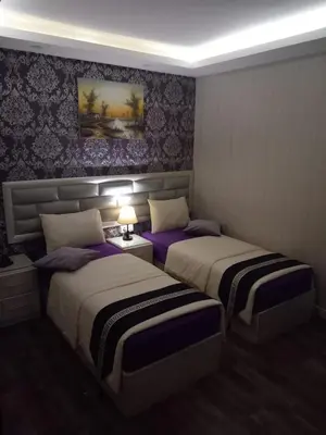 two beds in a room with purple walls at Beirut Hotel 1 in Amman