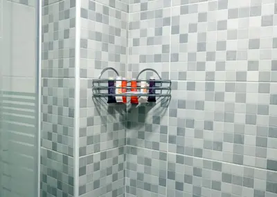 a bathroom with gray and white tiled walls and a rack of bottles at Beirut Hotel 1 in Amman