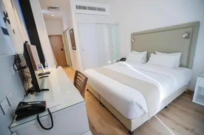 a bedroom with a white bed and a desk with a television at La Locanda Boutique Hotel in Amman