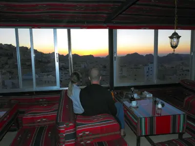 a man and woman sitting in a restaurant looking at the sunset at Petra Gate Hotel in Wadi Musa