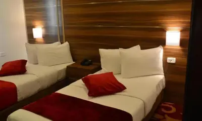 two beds in a hotel room with red and white pillows at Spark Plaza Hotel in Amman