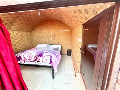 a small bedroom with a bed in a room with a door at Bedouin Lifestyle Camp in Wadi Rum