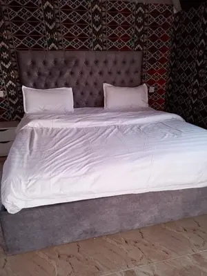 a large bed with white sheets and pillows at Joy to Wadi Rum in Wadi Rum