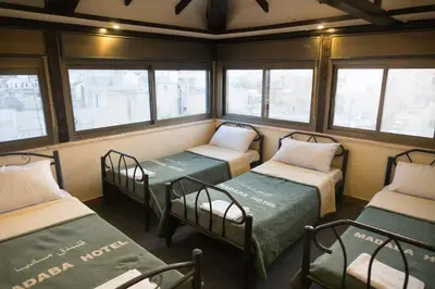 a room with three bunk beds and windows at Madaba Hotel in Madaba