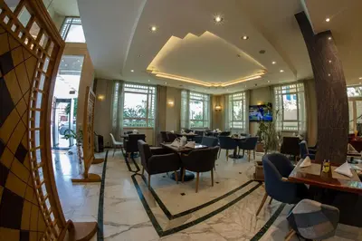 a restaurant with tables and chairs and windows at Kindi Suite Hotel in Amman